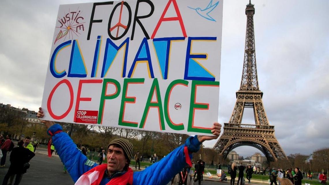 An activist holds a poster during a demonstration near the Eiffel Tower in Paris in 2015 during the United Nations Climate Change Conference. Opinion contributor Karin Klein says we can’t ignore the role of overpopulation in global warming.