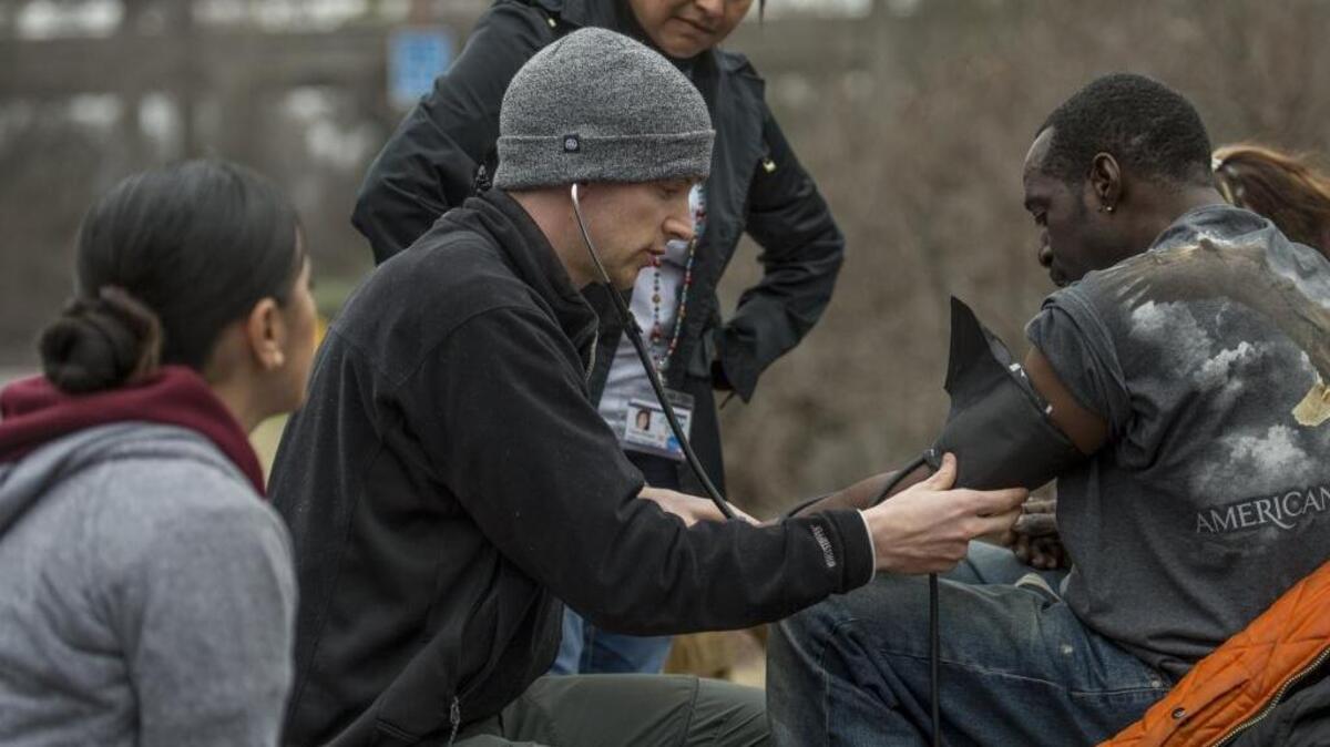 Abram Nunn with Elica Health checks the blood pressure of a homeless man in Sacramento in January.