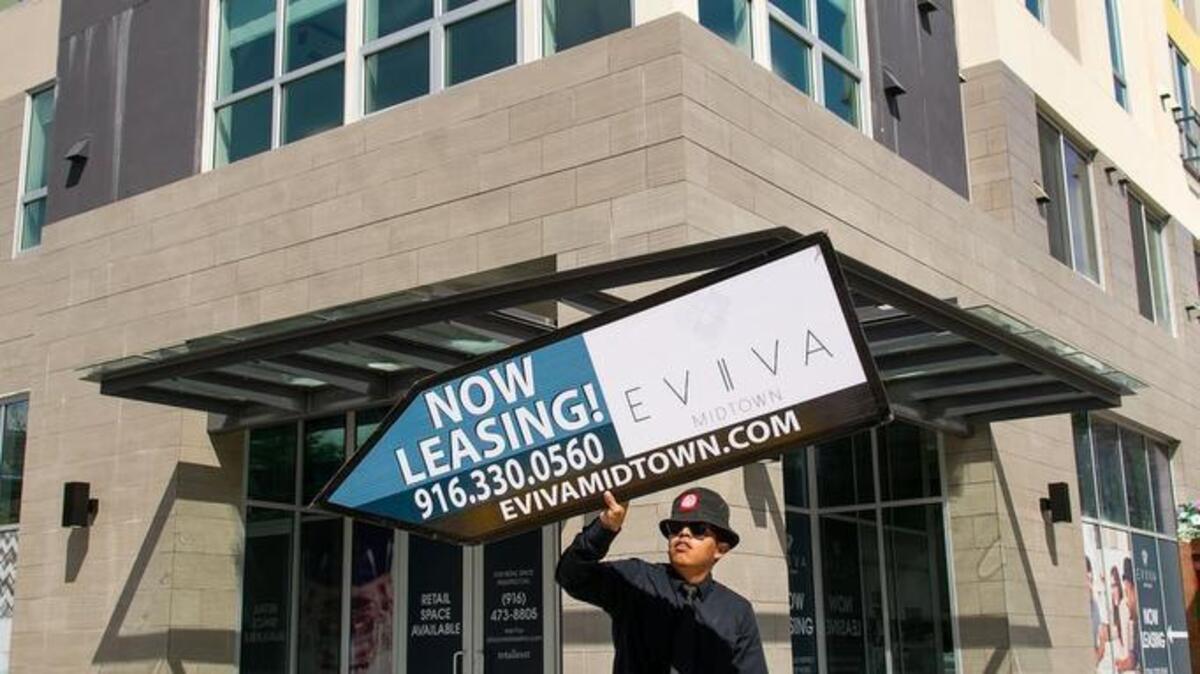 Manny Jacabo flips signs to draw the attention of passers-by to the new Eviva Midtown development, an urban mixed-use apartment development at 16th and N Streets in Sacramento.