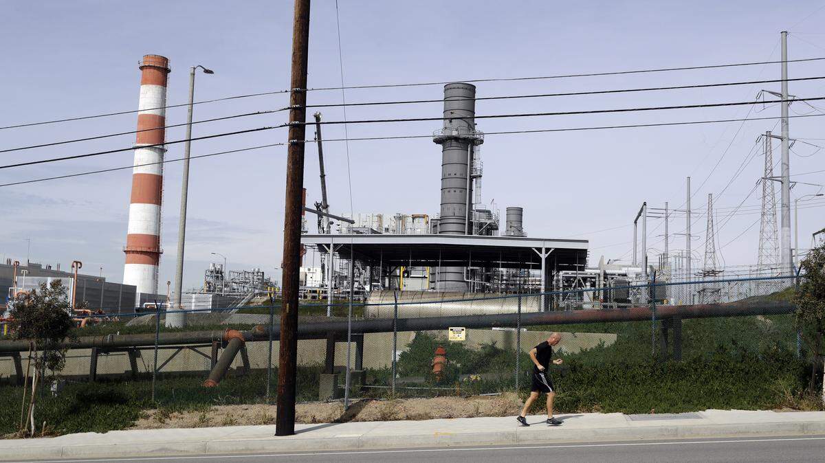 A jogger runs past the Scattergood power plant Tuesday, Feb. 12, 2019, in Los Angeles. Los Angeles will abandon a plan to spend billions of dollars rebuilding three natural gas power plants as the city moves toward renewable energy, Mayor Eric Garcetti said Monday. (AP Photo/Marcio Jose Sanchez)