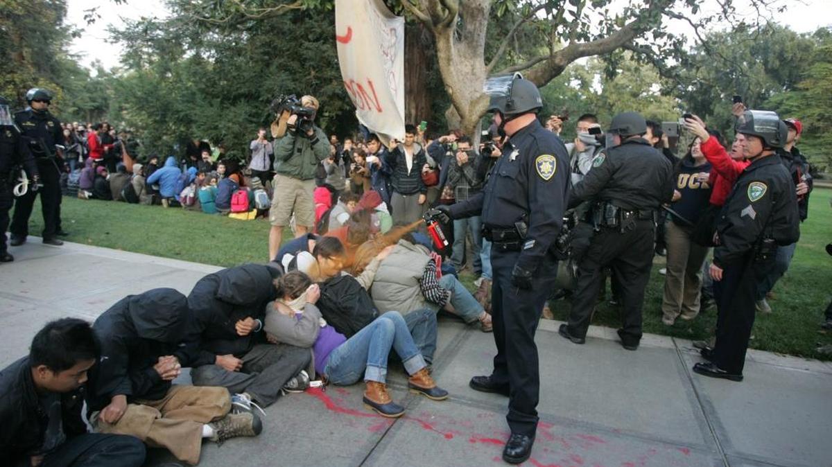 A UC Davis police officer uses pepper spray as he walks down a line of Occupy demonstrators sitting on the ground at the University of California, Davis on Friday, Nov. 18, 2011.