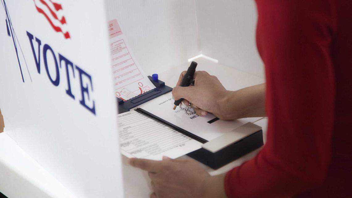 A voter pushes a pin to indicate a vote on a ballot in a voting center during an election.
