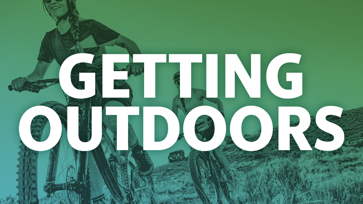 Getting outdoors: Two women ride mountain bikes through open field