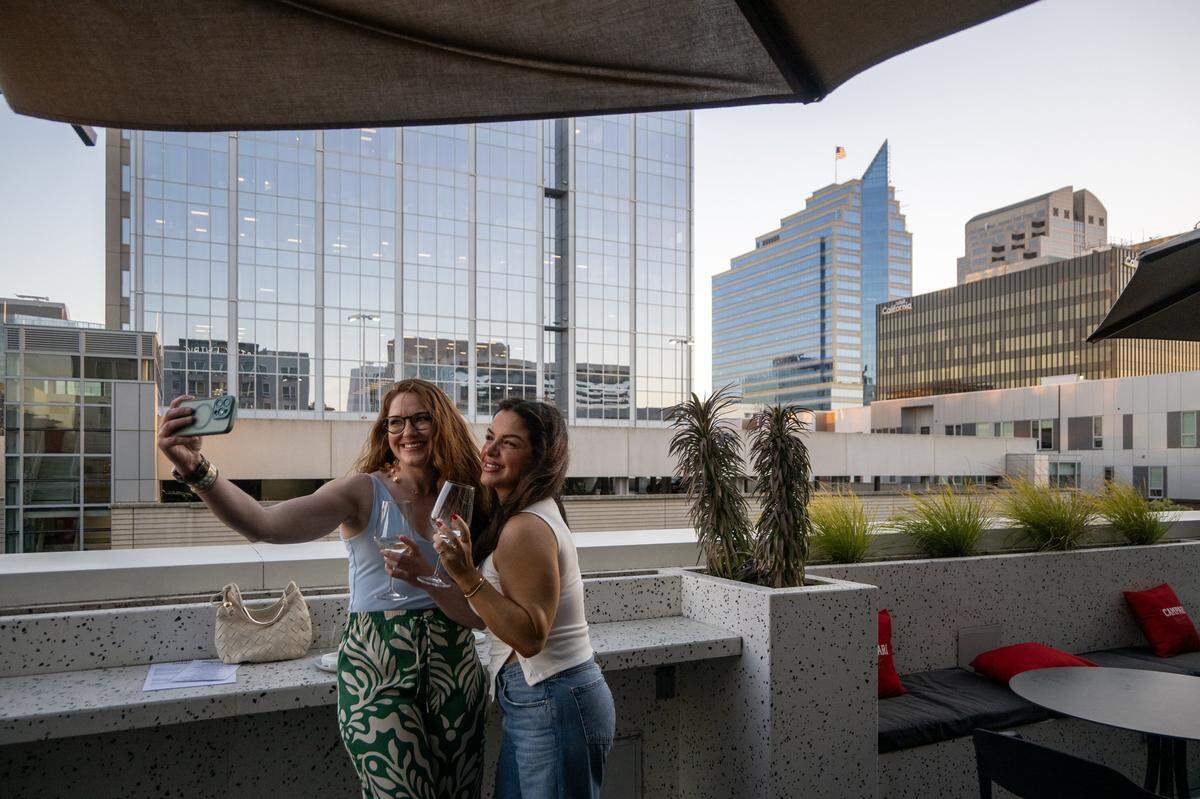 Sarah Taber takes a photograph with her friend Mona Kaldani at the rooftop bar at the Clayton Club in downtown Sacramento earlier this month.