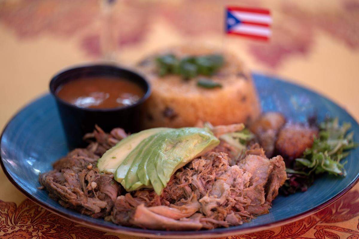 The Puerto Rican Special ($22), featuring roast pork, seasoned rice and plantains, is served at Lola’s Lounge on 16th Street near Broadway in Sacramento.