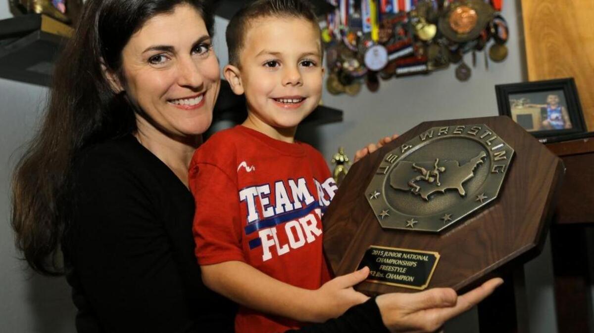 In this Tuesday, Feb. 9, 2016 photo, Toni Bouzakis, left, and her son Greco Roman, hold a wrestling trophy at their home in Lutz, Fla., that was given to them in 2015 by Larry Early III. Early, a Minnesota freshman, is redshirting on the Gophers wrestling team this season, but he still has a lot to wrestle for, his 5-year-old friend Greco. Greco Roman Bouzakis has a rare form of terminal brain stem cancer found in children. They met through social media and have been improbable pals for the past year.