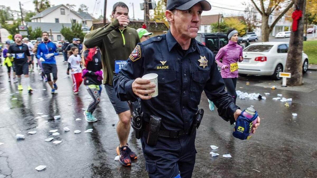 Folsom police Officer Eric Baade grabs water as he runs through Fair Oaks Village during the California International Marathon, Sunday, December 6, 2015.