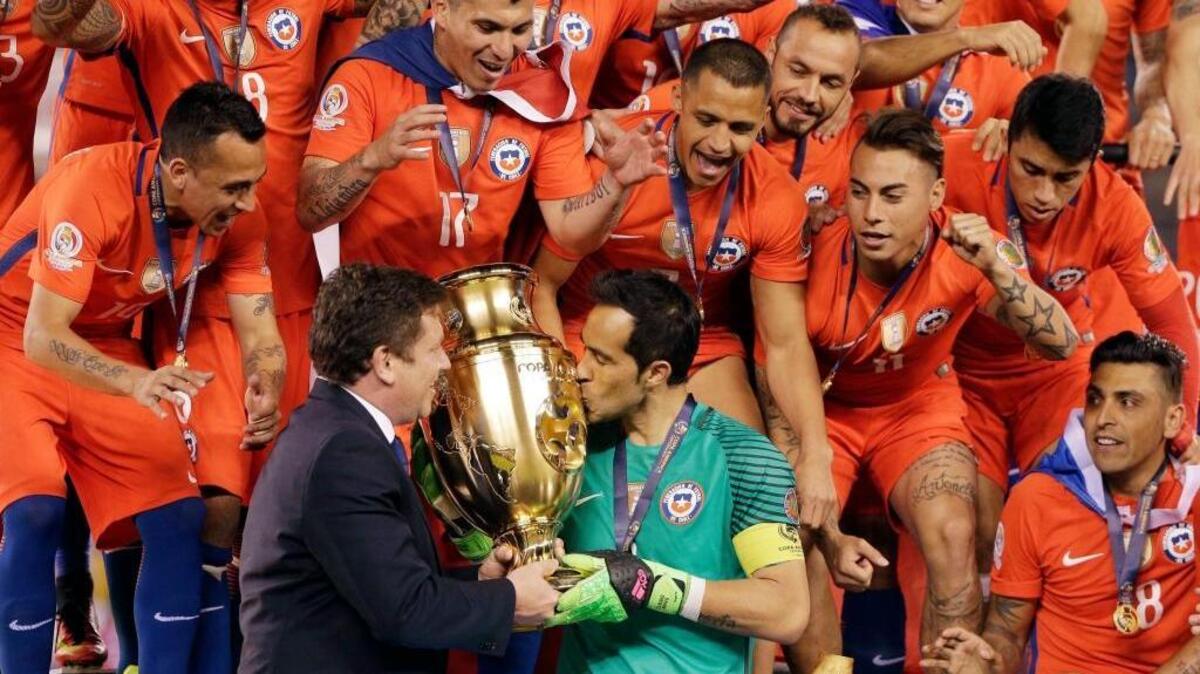Teammates watch as Chile goalkeeper Claudio Bravo kisses the trophy after the Copa America Centenario championship soccer match on Sunday, June 26, 2016, in East Rutherford, N.J.