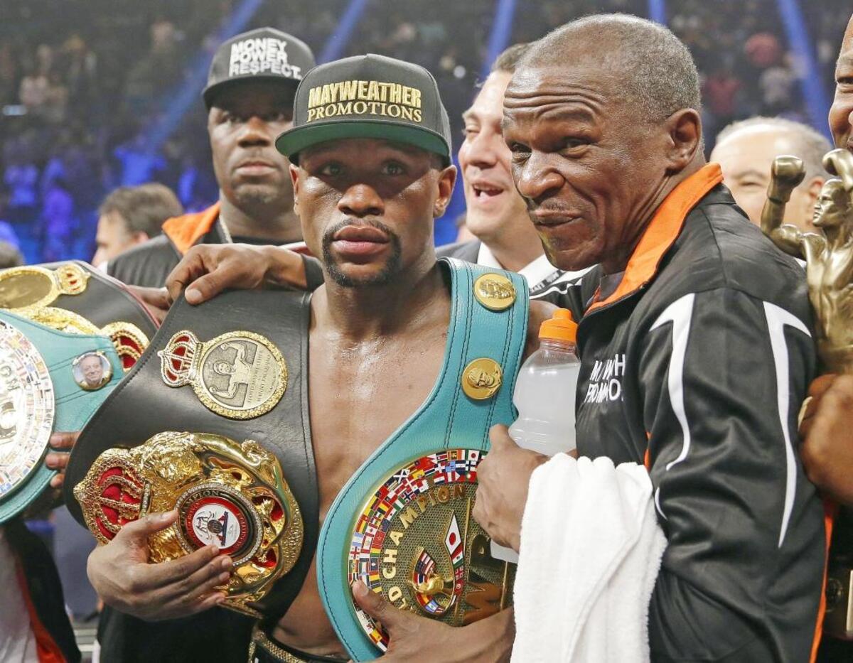 Undefeated boxer Floyd Mayweather Jr., left, poses with his championship belts and his father, head trainer Floyd Mayweather Sr., after a fight on May 2, 2015, in Las Vegas.