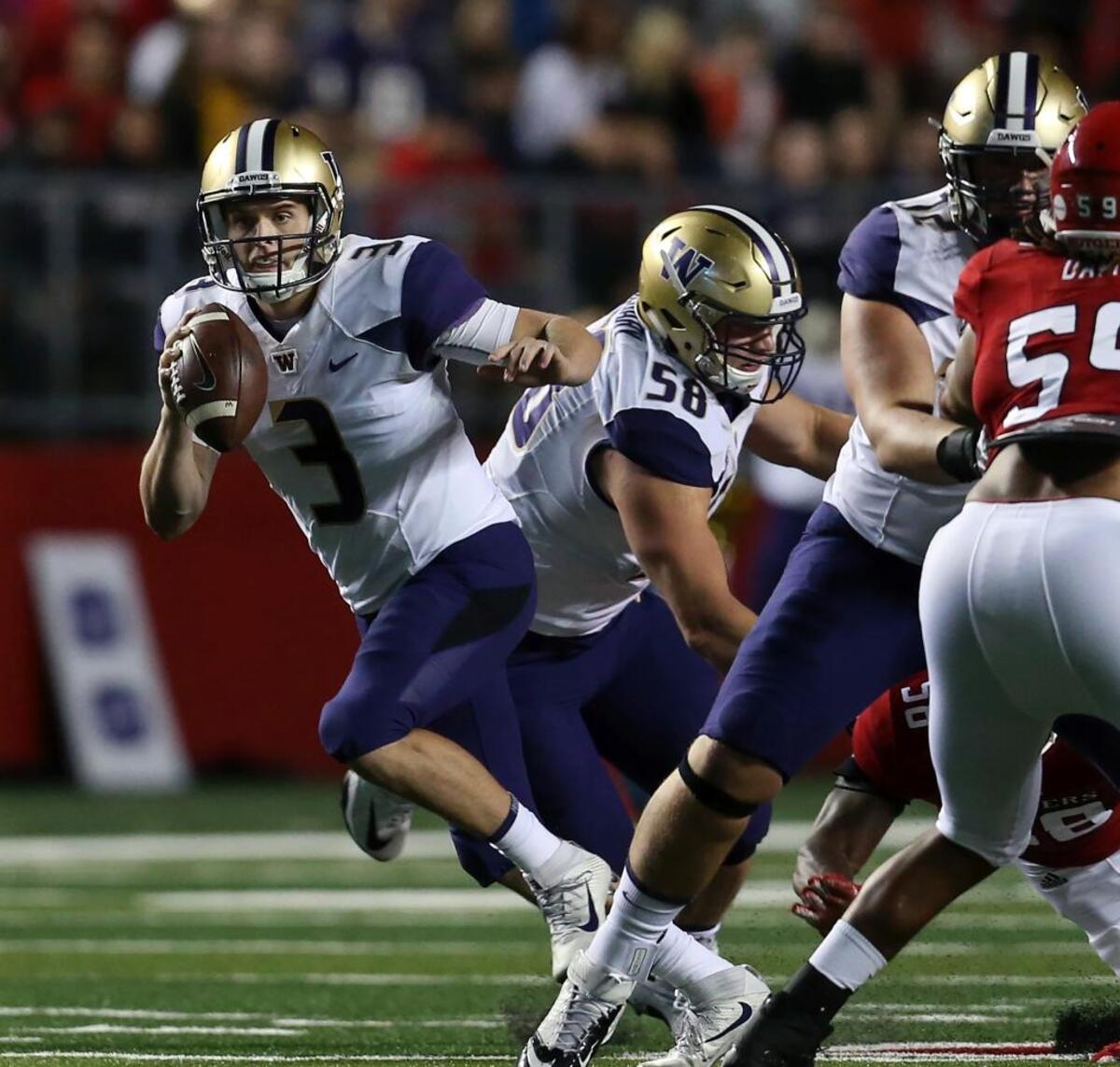 Washington quarterback Jake Browning, left, looks to pass against Rutgers on Friday in Piscataway, N.J. Browning was hit hard on a first-quarter sack bu finished 17-of-30 passing with two touchdowns in a 30-14 victory.