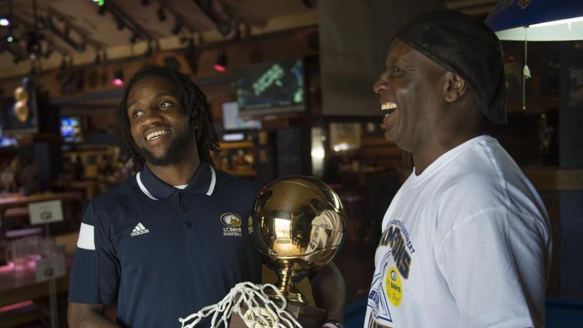 UC Davis men’s basketball senior guard Darius Graham, left, holds the Big West Conference Tournament title trophy while standing with his father, Sebastian Graham, on Sunday, March 12, 2017, at the Davis Graduate sports bar and restaurant.