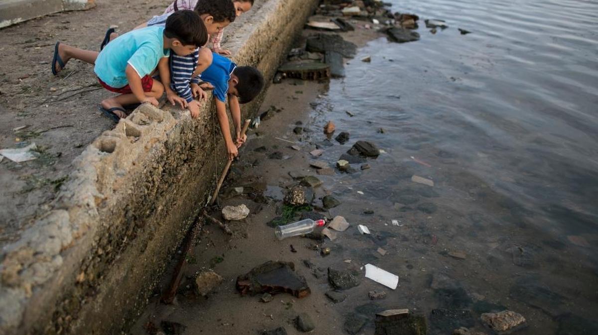 Children try to catch a crab as they play on the polluted shore of Guanabara Bay in Rio de Janeiro, Brazil, Saturday, July 30, 2016. In Rio, the main tourist gateway to the country, a centuries-long sewage problem that was part of Brazil’s colonial legacy has spiked in recent decades in tandem with the rural exodus that saw the metropolitan area nearly double in size since 1970. The Summer Olympics begin Friday, Aug. 5, 2016 in Rio.