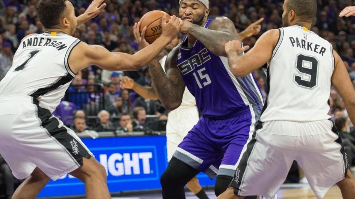 Sacramento Kings center DeMarcus Cousins, center, is fouled as he drives to the basket against San Antonio Spurs forward Kyle Anderson, left, and guard Tony Parker during the first regular-season game at Golden 1 Center on Thursday, October 27, 2016, in Sacramento, Calif.