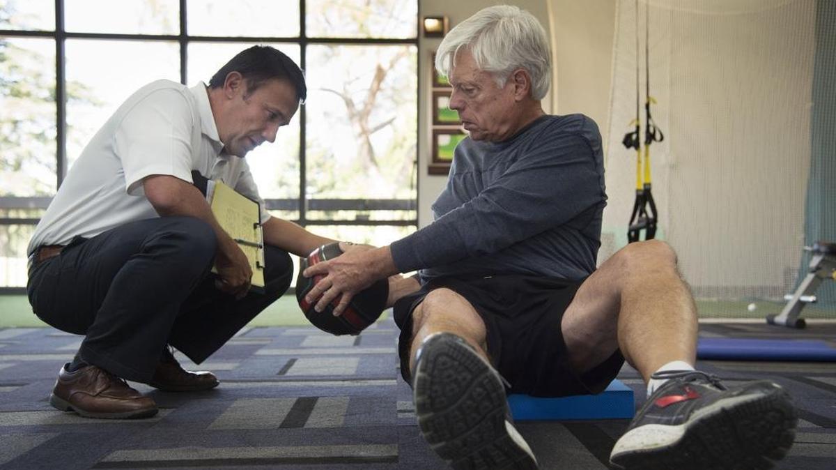 Fitness trainer Charles Burton, left, works with Phil Shaver, 73, of Davis who participates in a core strengthening exercise in a building dedicated to fitness training at the Ancil Hoffman golf course on Sept. 21 in Sacramento. Golf-specific fitness for players 50-80 is on the rise as older players are doing everything they can to be flexible, strong and competitively relevant as they attempt to stave off the effects of older age.