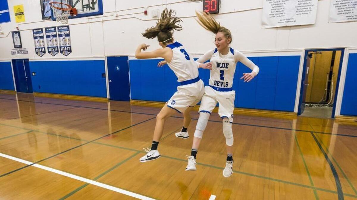 Davis High School Lady Blue Devils Alex Agnew (3) and teammate Cristina Oliva (2) jump together after they were introduced before facing the Sheldon Huskies on Wednesday.