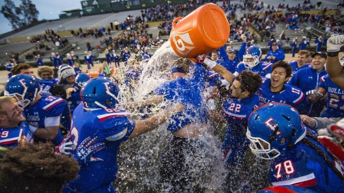 Folsom coach Kris Richardson is doused with water after the Bulldogs beat the St. Mary’s Rams 50-21 in the Sac-Joaquin Section Division I championship game Saturday at Hornet Stadium at Sacramento State.