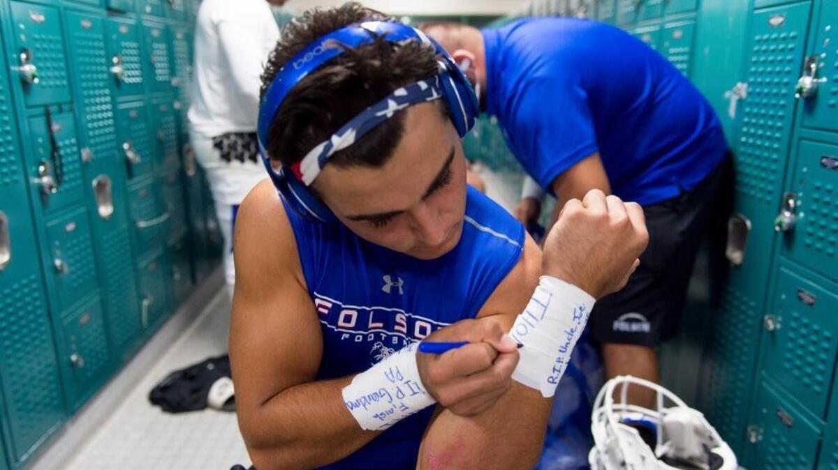 Folsom’s Tanner Ward writes the names of his relatives who have died on his wrist tape before facing Granite Bay on Sept. 29.