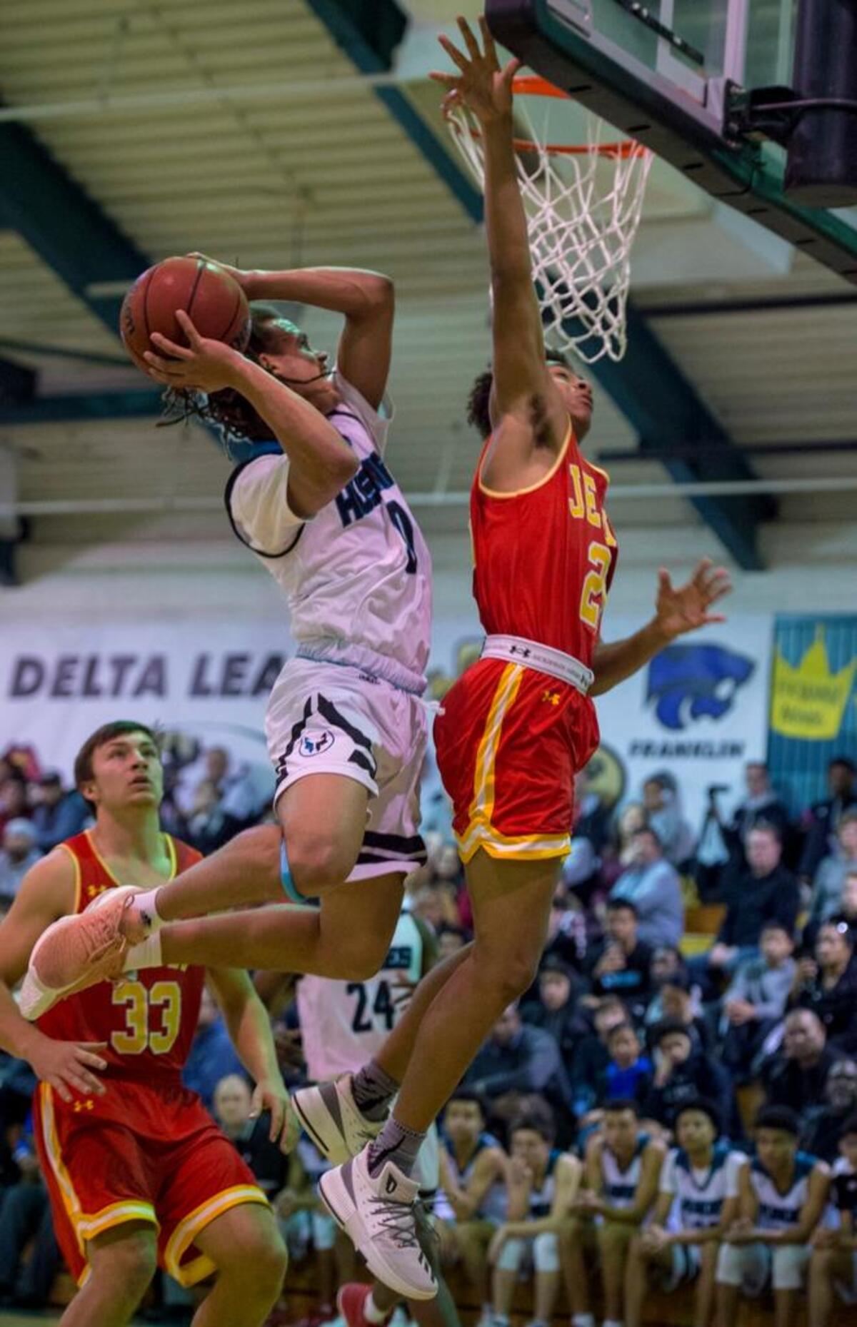 Sheldon Huskies guard Dale Currie (0) evades Jesuit Marauders Branden Rutherford (23) as he scores a basket in the first half on Friday at Sheldon High School.