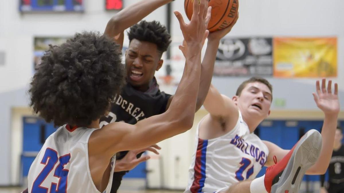 Woodcreek High School Timberwolves’ Jordan Brown grabs the rebound between Folsom’s Mason Forbes (25) and Brendan Patch (21) on Friday.