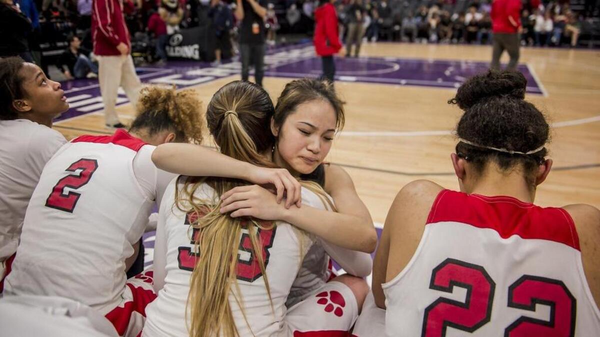 McClatchy Lions guard Sara Shimizu (14) embraces teammate Jordan Cruz (33) after the Lions fell 53-41 to Windward of Los Angeles in the CIF Division I state championship game on Friday.