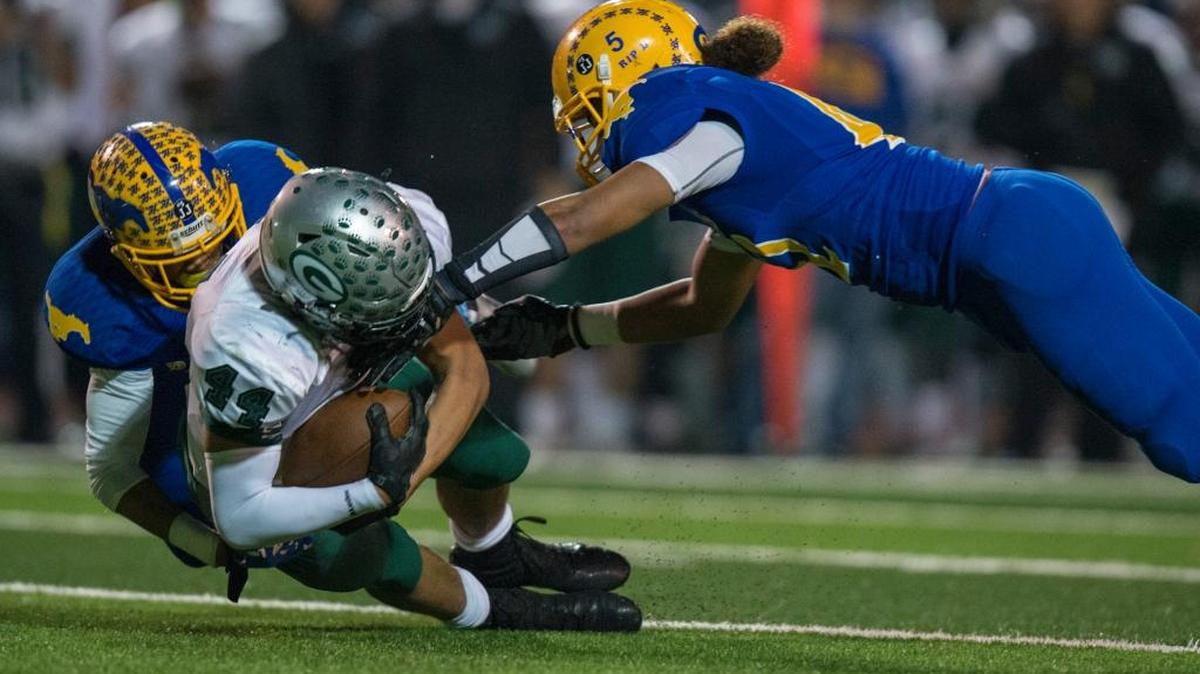 Granite Bay’s Alex Martinez (44) is tackled by two Grant defenders during their Sac-Joaquin Section Division II football playoff game Sacramento on Saturday.