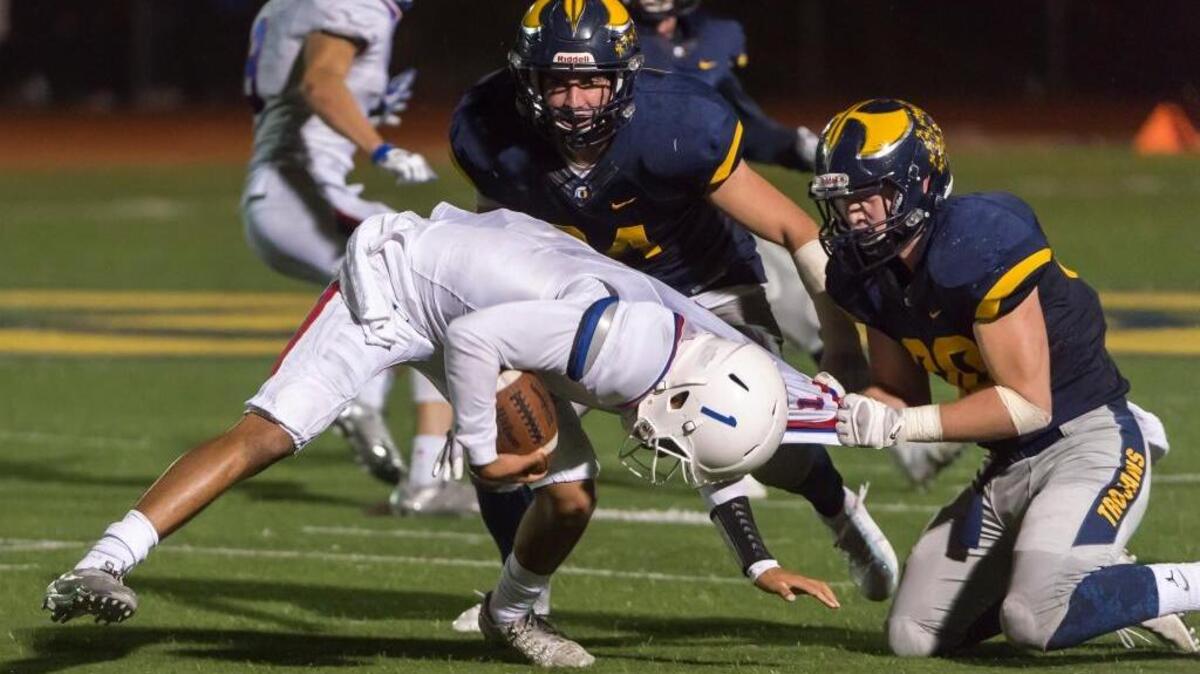 Oak Ridge Trojans’ Sam Sanders (30) pulls the jersey of Folsom Bulldogs’ Kaiden Bennett (1) during the fourth quarter Friday.