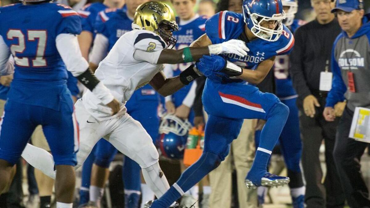 Folsom’s Drake Stallworth (2) tries to escape a tackle by Elk Grove’s Julius Fullah on Saturday. The Bulldogs won their fifth section title since 2010.