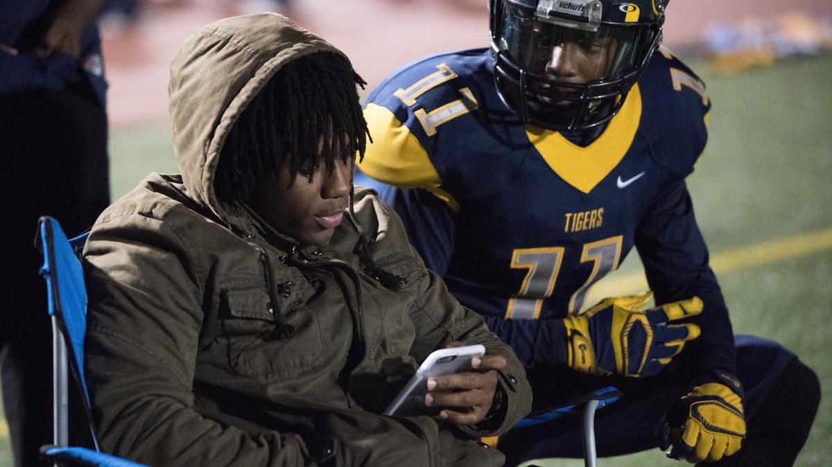 Out with a leg injury, Inderkum’s Derrick Henderson, left, checks cellphone messages with teammate Ryan Davis.