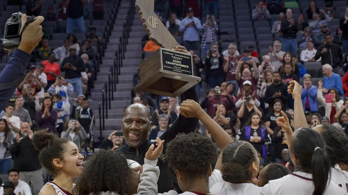 West Campus Warriors head coach John Langston holds the trophy over the heads of his players following the Division IV girls state basketball championship game with the Los Osos Grizzlies at Golden 1 Center in Sacramento on Saturday. The Warriors won the title 63-55.