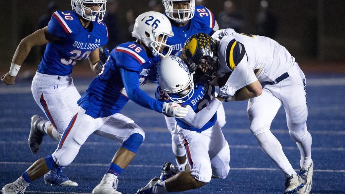 Oak Ridge Trojans Rhys Kennedy (22), is gang tackled by the Folsom High School Bulldogs defense during the first quarter as the Folsom High School Bulldogs varsity football team host the Oak Ridge High School Trojans, Friday, Nov. 4, 2016.