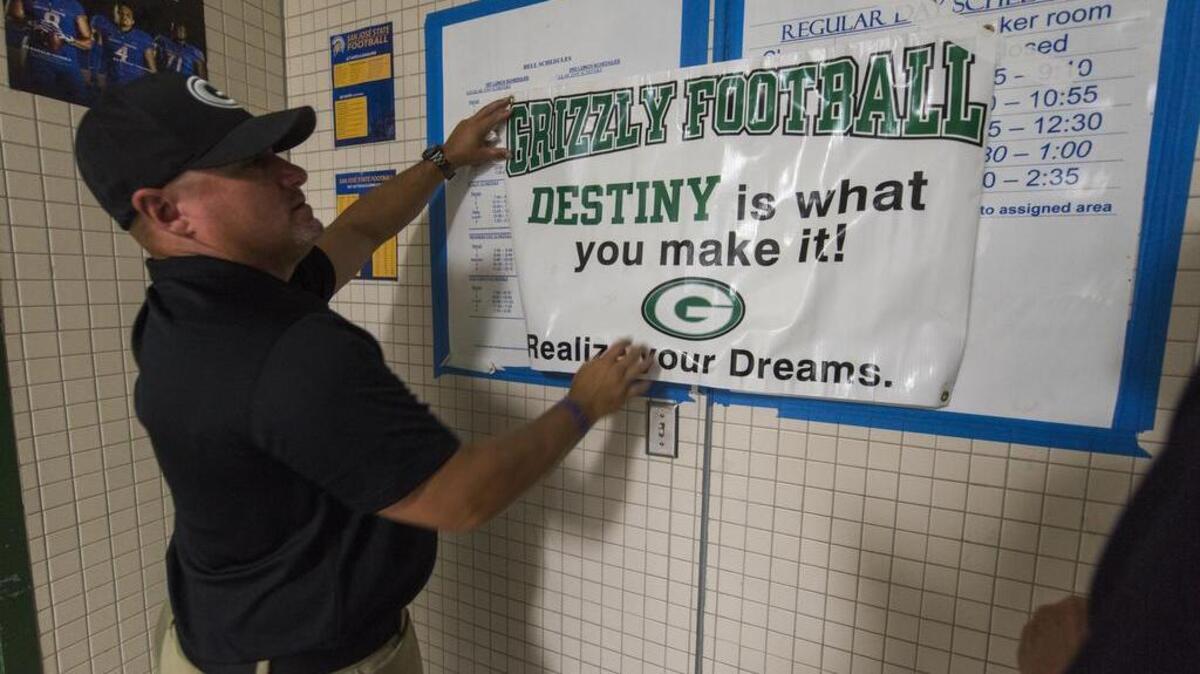Granite Bay Grizzly head coach Jeff Evans puts up a sign inside the locker room as Granite Bay hosts Del Oro on Friday, Sept. 14, 2018.