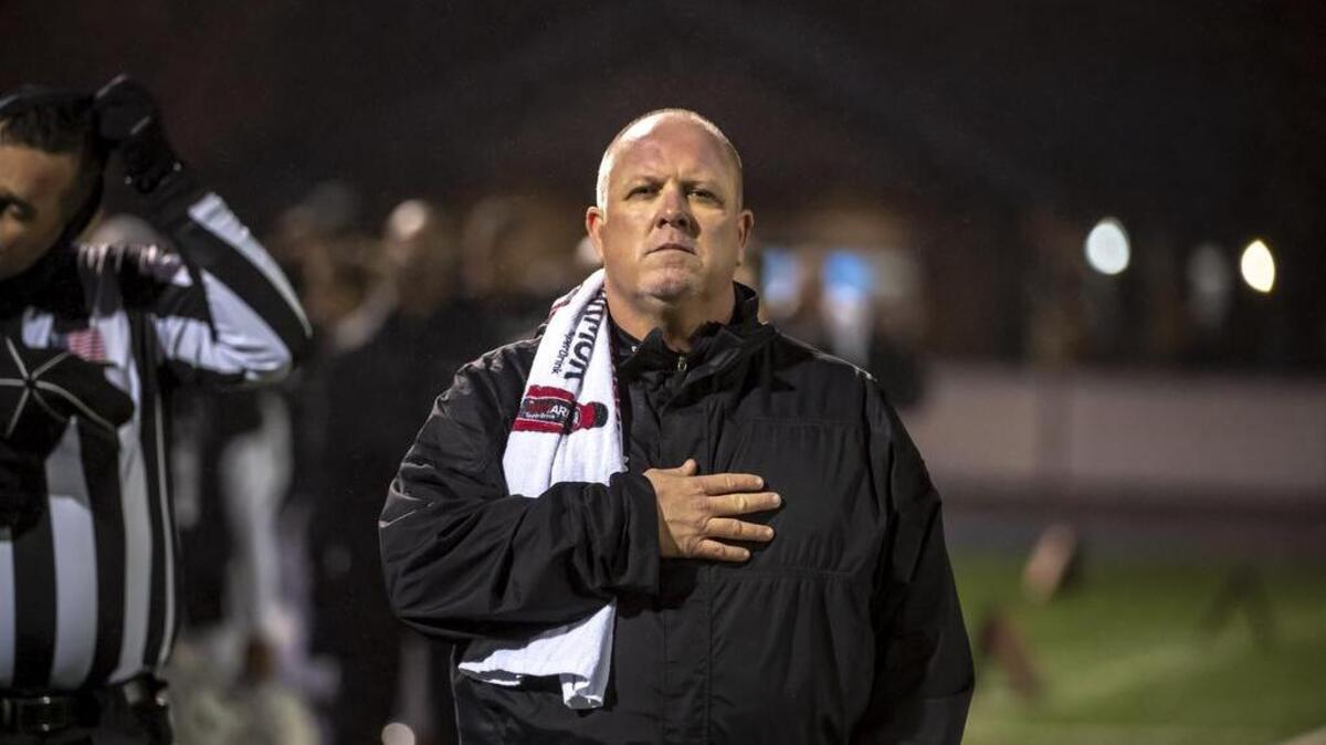 Capital Christian Cougars head coach Casey Taylor honors the flag in the run before the game.