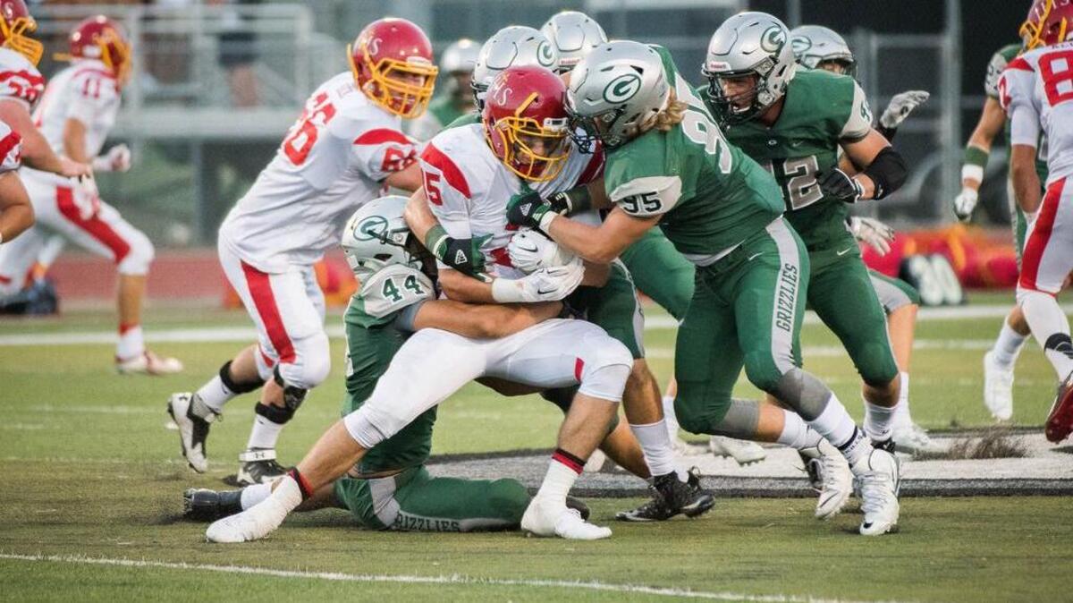 
Jesuit's Beau Bisharat (35) is taken down by Grizzlies Alex Martinez (44) and Jared Baer (95).
