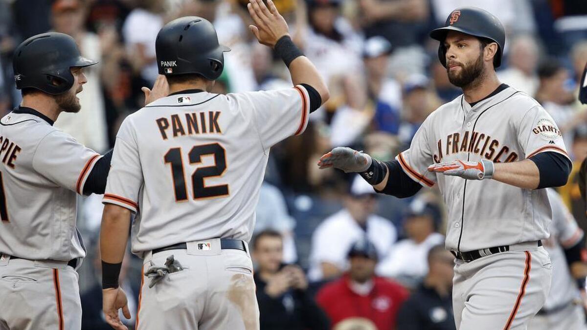 Giants first baseman Brandon Belt, right, is greeted by teammates Conor Gillespie, left, and Joe Panik after hitting a grand slam against the San Diego Padres on Friday in San Diego.
