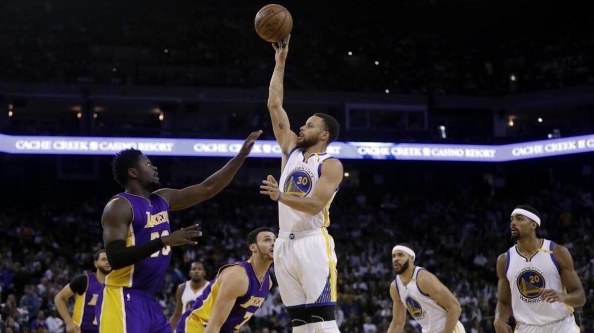Golden State Warriors’ Stephen Curry, center, shoots over Los Angeles Lakers’ Julius Randle, left, during the second half of an NBA game Wednesday, April 12, 2017, in Oakland, Calif.