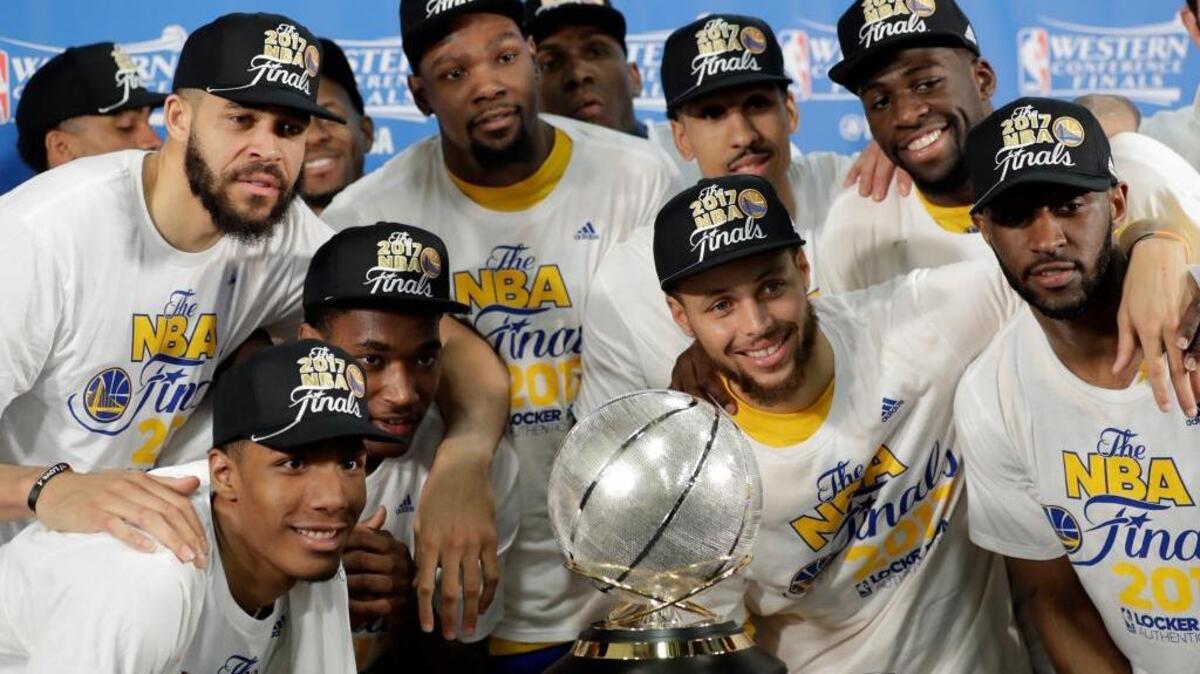 Golden State Warriors players pose around their trophy for winning the Western Conference finals following their 129-115 victory over the San Antonio Spurs on Monday. They’ll meet either the Cleveland Cavaliers or Boston Celtics in the NBA Finals.