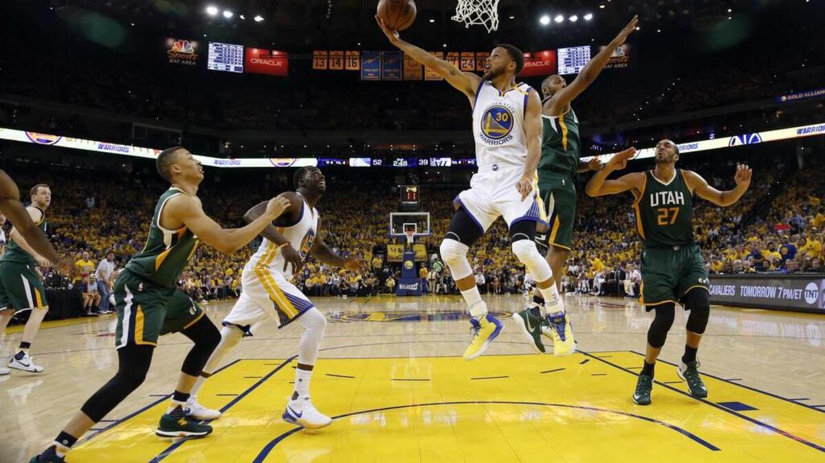 Stephen Curry (30) goes up and under against the Jazz in the first half Tuesday night. Curry led the victorious Warriors with 22 points.