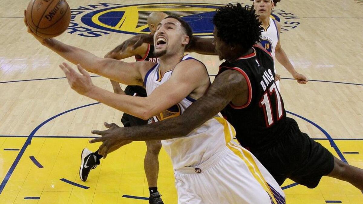 Golden State Warriors guard Klay Thompson, front left, is fouled by Portland Trail Blazers center Ed Davis while scoring during the second half in Game 1 of a second-round NBA basketball playoff series in Oakland, Calif., on Sunday, May 1, 2016.