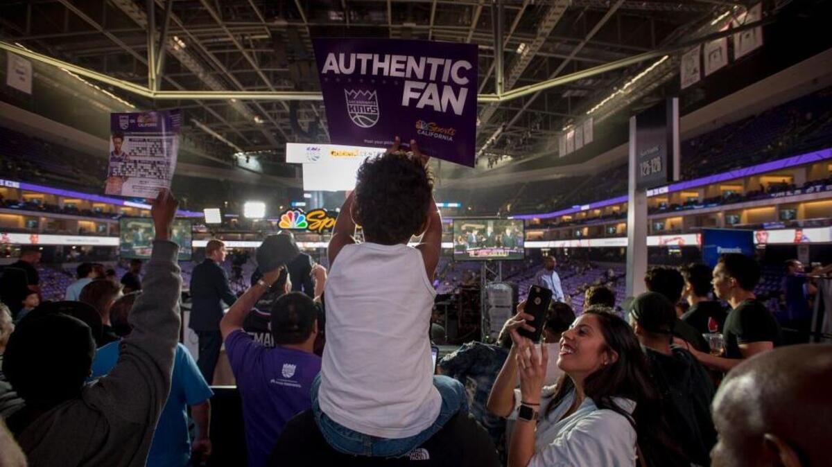 Alejandra Guria, right, photographs her son, Ethan, 4, as father David Guria holds him up for a better look before Wednesday’s Kings game against the Houston Rockets at Golden 1 Center.