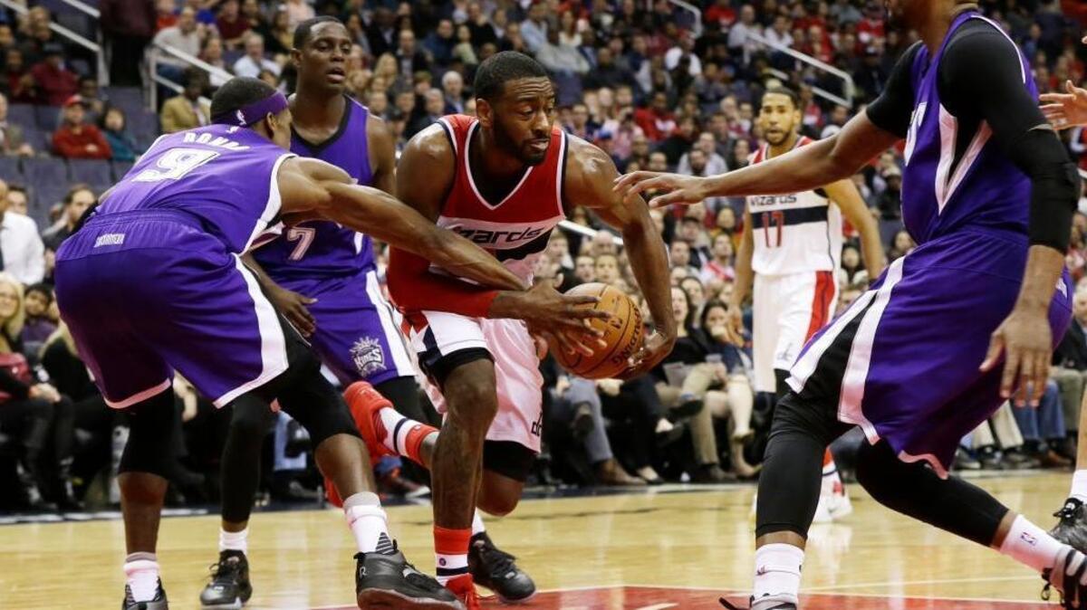 Washington Wizards guard John Wall (2) fights for the ball as he drives through Sacramento Kings guard Rajon Rondo (9), guard Darren Collison (7) and forward Rudy Gay during an NBA basketball game Monday, Dec. 21, 2015, in Washington.