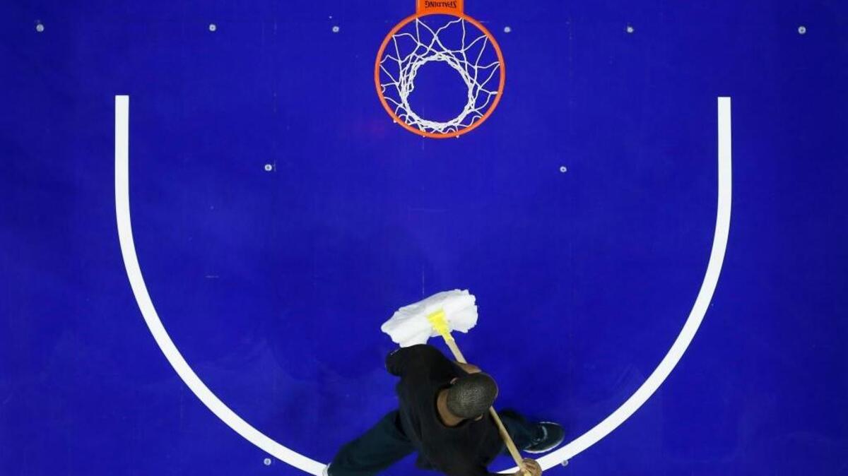 A building worker walks across the court before an NBA basketball game between the Philadelphia 76ers and the Sacramento Kings, Wednesday, Nov. 30, 2016, in Philadelphia. The game was delayed because of the court’s unsafe surface issue. And so it went for the Kings in a winless week.