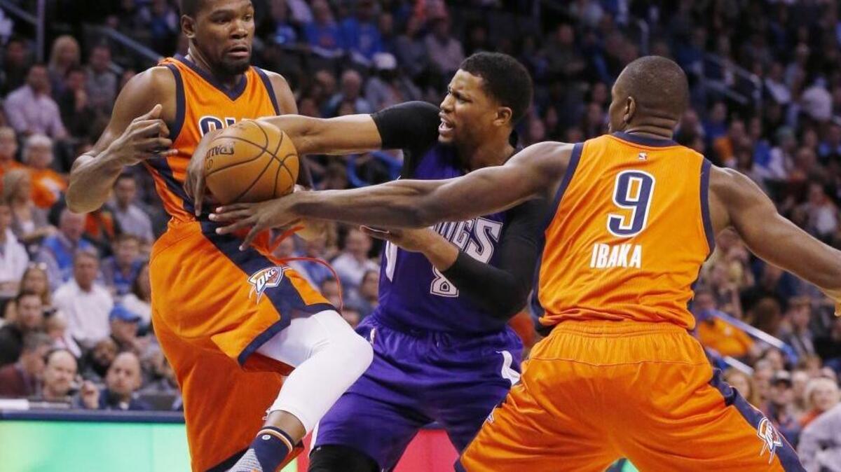 Oklahoma City Thunder forward Kevin Durant, left, and forward Serge Ibaka (9) reach for the ball held by Kings forward Rudy Gay in the first quarter Sunday, Dec. 6, 2015, in Oklahoma City.