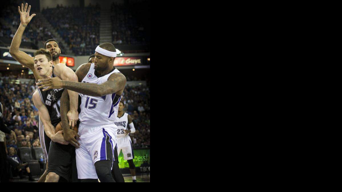 
Kings center DeMarcus Cousins fights for the ball against San Antonio’s Aron Baynes and Tim Duncan. Despite early foul trouble, Cousins had game highs of 25 points and 10 rebounds.
