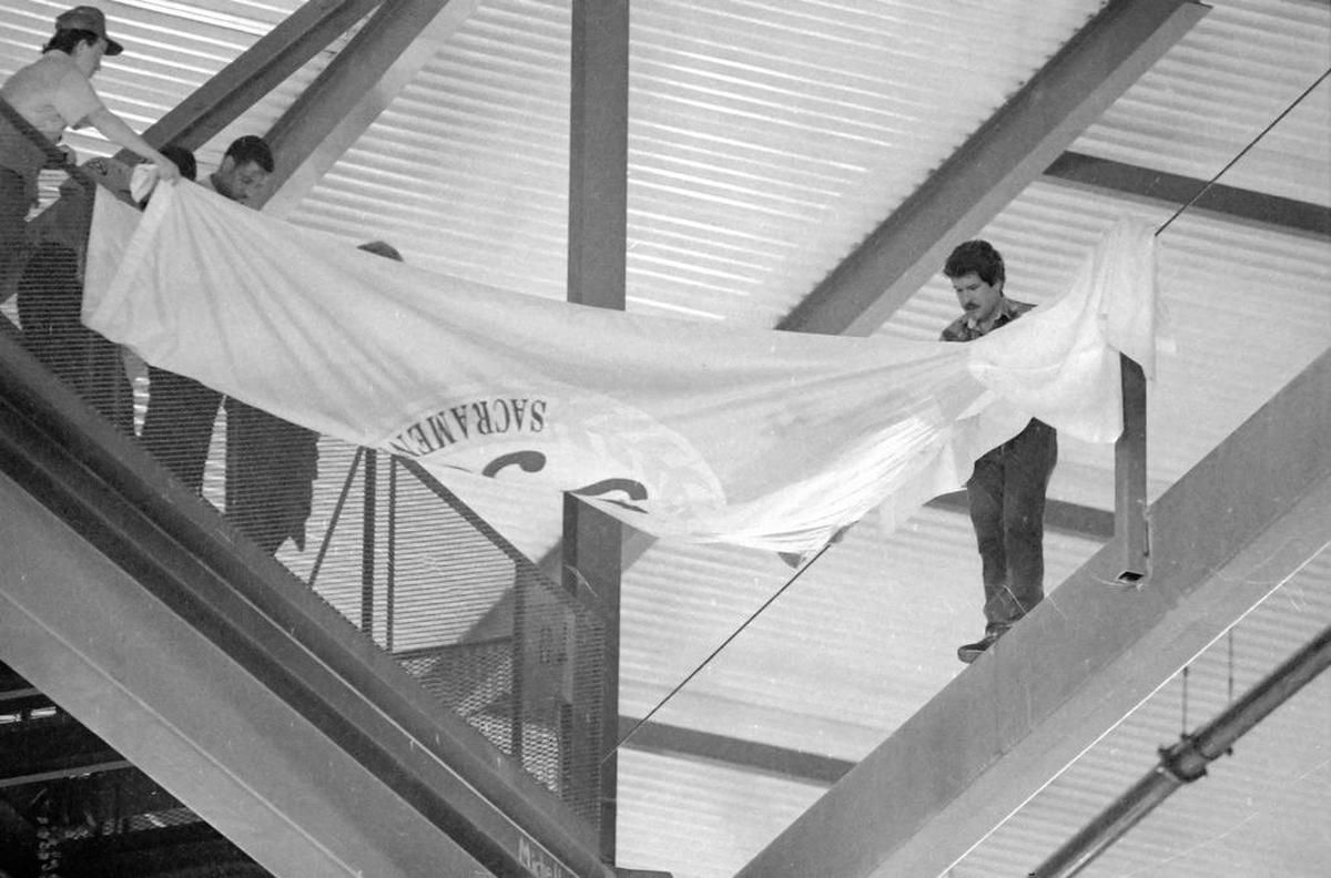Sacramento Kings owner Gregg Lukenbill unfurls a banner while standing on a beam in Arco Arena in an attempt to keep rain which had leaked through the roof from reaching the playing surface below in 1989. Rain on the playing surface caused a delay of more then 40 minutes. When the game was resumed, the Kings found themselves losing to the Philadelphia 76ers 114-111.