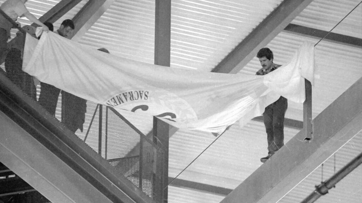 Sacramento Kings owner Gregg Lukenbill unfurls a banner while standing on a beam in Arco Arena in an attempt to keep rain which had leaked through the roof from reaching the playing surface below on March 1, 1989. Rain on the playing surface caused a delay of more then 40 minutes. When the game was resumed, the Kings found themselves losing to the Philadelphia 76ers 114-111. 