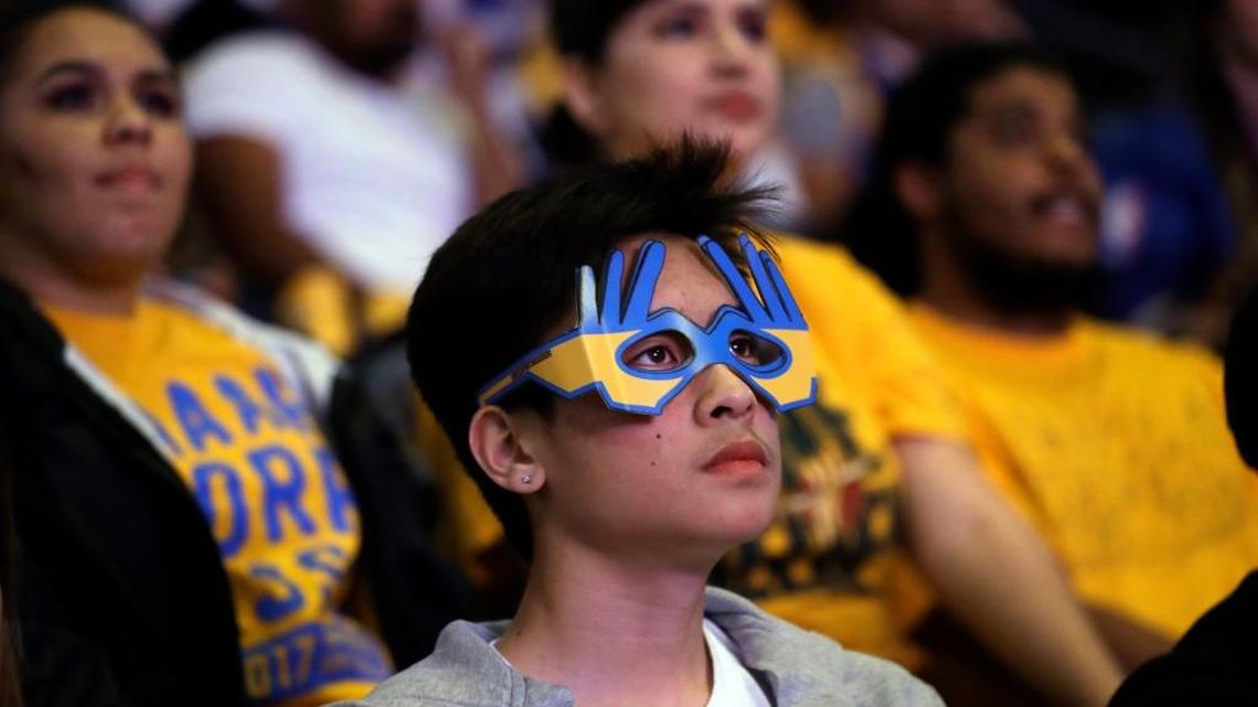 A fan watches the broadcast of Game 4 of basketball’s NBA Finals between the Golden State Warriors and the Cleveland Cavaliers, Friday, June 9, 2017, at Oracle Arena in Oakland, Calif. One fan paid $90,000 for a pair of tickets to Game 5.