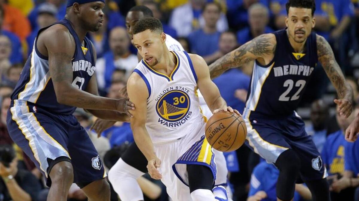 Warriors guard Stephen Curry dribbles between Memphis Grizzlies forward Zach Randolph, left, and forward Matt Barnes during the first half of Wednesday night’s 125-104 victory in Oakland.