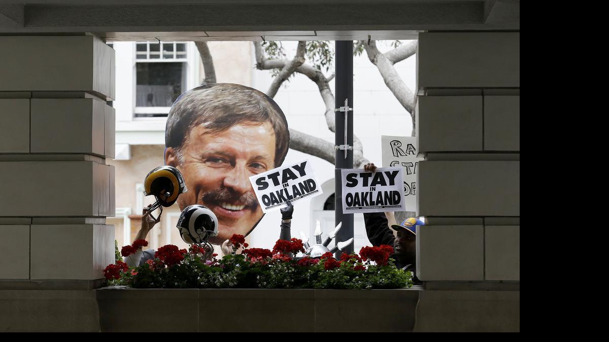 
A photo of St. Louis Rams owner Stan Kroenke, left, is held up by Rams fans as they rally with San Diego Chargers and Oakland Raiders fans outside of the NFL's spring football meetings in San Francisco, Tuesday, May 19, 2015.
