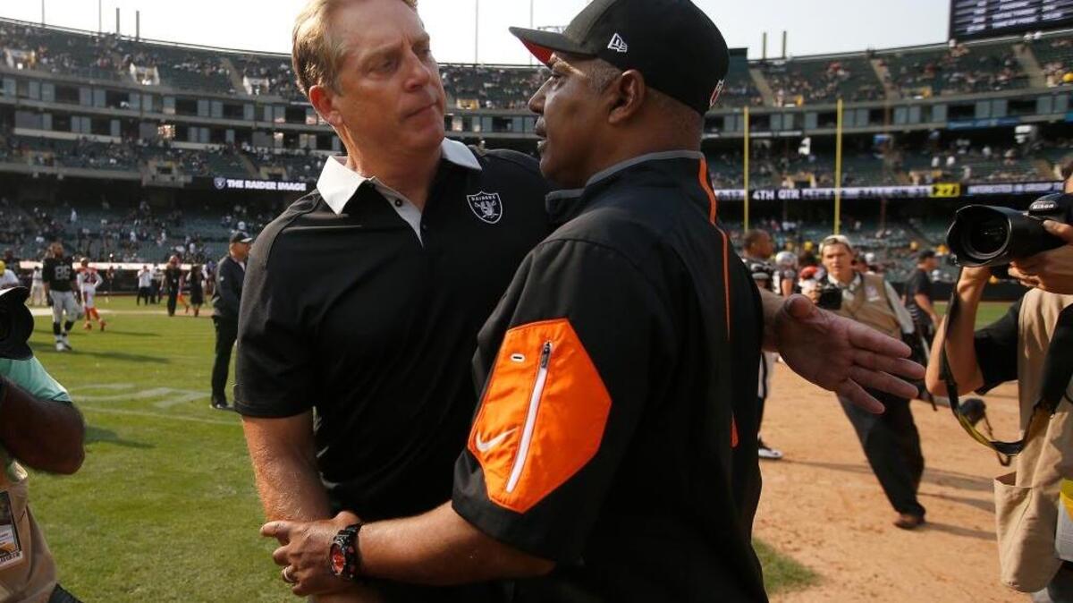 Raiders coach Jack Del Rio, left, greets Cincinnati Bengals coach Marvin Lewis near the dirt on the Coliseum field on Sept. 13, 2015. Because the Raiders share their home field with the A’s, the infield dirt stays until the baseball team’s season ends.