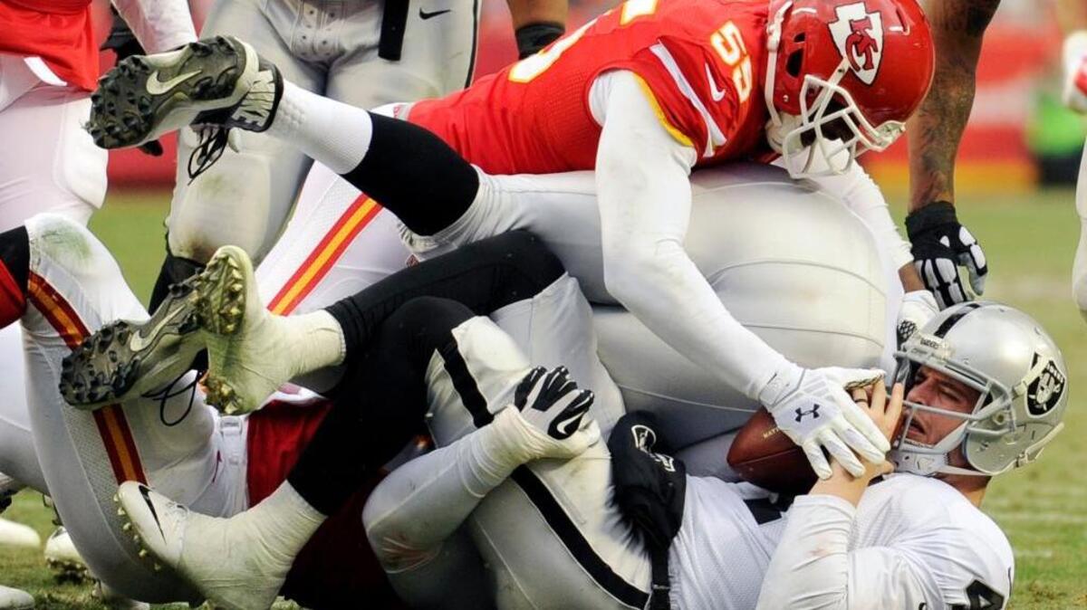 Oakland Raiders quarterback Derek Carr, bottom, is tackled by Kansas City Chiefs linebacker Dee Ford (55) during an NFL football game in Kansas City, Mo., Sunday, Dec. 14, 2014. The Raiders lost 31-13, just three weeks following their 24-20 win over the Chiefs in Oakland.